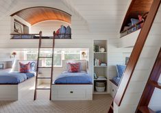 two bunk beds in a room with white walls and wood trimming on the ceiling