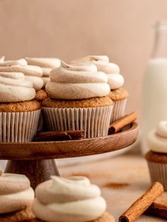 cinnamon cupcakes with white frosting and cinnamon sticks on a cake platter