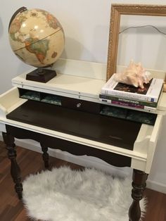 a white desk with books and a globe on top