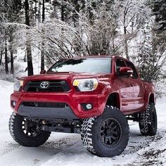 a red toyota truck driving down a snow covered road