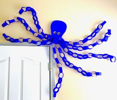 an octopus made out of blue plastic chains hangs on the wall next to a door