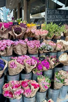 many different types of flowers are on display in buckets at the flower shop for sale