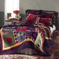 a bed covered in a colorful quilt and pillows