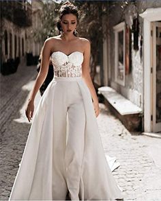 a woman is walking down the street wearing a white wedding dress and high - waisted pants