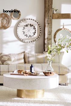 a living room filled with furniture and plates hanging on the wall above it's coffee table