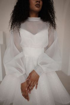 a woman wearing a white dress with sheer sleeves