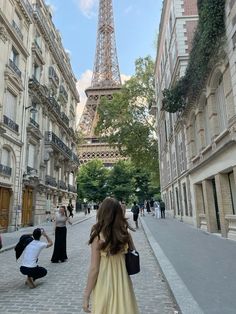 a woman in a yellow dress is taking a picture of the eiffel tower