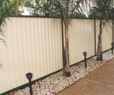 there is a fence that has some plants growing on it and rocks in the ground