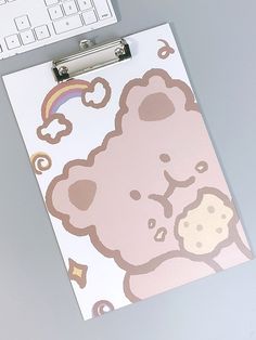 a clipboard with a cartoon bear on it next to a computer keyboard and mouse