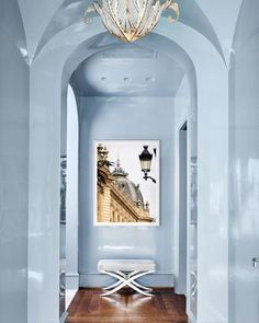 a hallway with a chandelier and blue walls in the center, along with wooden flooring