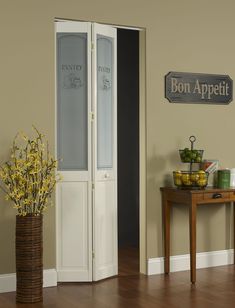 a room with a table, vase and door on the wall that says bon appetit