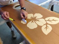 a man is using a sharpie to paint a flower design on a piece of cardboard