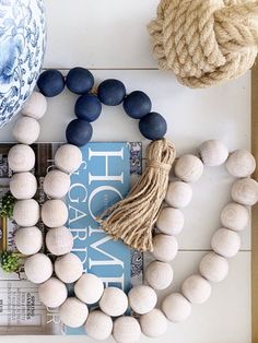 a white and blue wreath with tassels on top of it next to a book