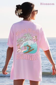 "This Hawaii Crewneck Comfort Colors shirt is perfect for those who love and travel to Hawaii. Featuring a vibrant surf design accented by hibiscus flowers, it's a colorful and comfortable addition to any wardrobe. The shirt proudly displays \"Aloha State Hawaii\" in bold funky retro letters, making it a great way to show your love for the beautiful state. ABOUT THE SHIRT Comfort Colors 1717 Unisex Jersey Short Sleeve 100% Ringspun Soft Cotton Fits True To Size Size UP 1-2 Sizes For An Oversized Look RETURN POLICY All items are made to order specially for you! We do not accept returns or exchanges unless the item is printed incorrectly. We want you to love your order, so please be sure to check size charts and ask any questions if you have any! Let me know if you have any questions at all! Casual Surfing Camp Shirt With Graphic Print, Casual Graphic Print Camp Shirt For Surfing, Beach T-shirt With Sublimation Print, Tropical Graphic Print T-shirt For Vacation, Pink Hawaiian Camp Shirt For Beach, Hawaiian Shirt With Letter Print, Hawaiian Short Sleeve Shirt With Letter Print, Casual Hawaiian Shirt With Graphic Print For Surfing, Hawaiian Shirt With Letter Print And Short Sleeves