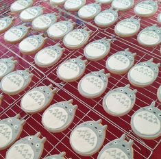 many decorated cookies sitting on top of a cooling rack in front of a red table