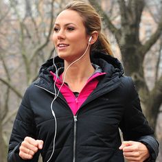 a woman running in the park listening to earbuds and headphones on her ears