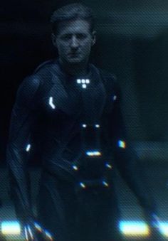 a man in a futuristic suit walking through the dark