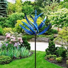 a blue metal sculpture sitting in the middle of a garden