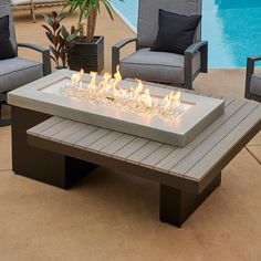 a fire pit sitting on top of a wooden table next to a swimming pool with lounge chairs