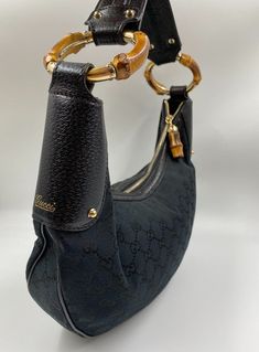 A Vintage Gucci Hobo made from black canvas with the GG monogram. Black leather trim with gold embossed logo and gold hardware. Iconic bamboo detail on the shoulder strap and zip pull. The inside of the bag is in perfect condition and features an interior zipped pocket for valuables. The external fabric of this bag is also in very good condition. The only wear that can be seen is on the leather shoulder strap which has some light creasing. Inside there is the serial number on the back of the lea Gg Monogram, Gucci Bamboo, Black Canvas, Embossed Logo, Leather Trim, Hobo Bag, Vintage Gucci, Leather Trims, Gucci Bag