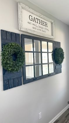 two mirrors mounted to the wall with wreaths hanging on them and a sign that says gather