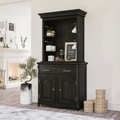 a black china cabinet sitting on top of a hard wood floor next to a fireplace