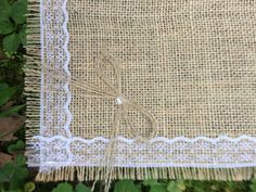 a close up of a piece of cloth with lace on it and green plants in the background