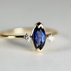 This beautiful natural blue sapphire is marquise shape and featuring in a 14k yellow gold prong setting and 14k yellow gold band. Diamonds are natural and sparkles. There are two clear diamonds each sides.The three stones represent (also called the Trinity or trilogy ring) represents friendship, love, and fidelity, or past, present, and future. DETAILS ABOUT THE RING, MATERIAL AND STONES***Center sapphire is marquise cut , 0.95 carat weight, 8 X 4mm.*** Sides diamonds are 2 mm size and 0.06 cara 14k Gold Marquise Cut Sapphire Promise Ring, Marquise Sapphire Promise Ring Jewelry, Classic Blue Marquise Diamond Ring, 14k Gold Marquise Cluster Ring, Marquise Cluster Ring In 14k Gold, Classic Blue Marquise Sapphire Ring, Sapphire Diamond Ring Marquise Cut Gift, Marquise Yellow Gold Birthstone Ring In Fine Jewelry Style, Sapphire Marquise Cut Diamond Ring Gift