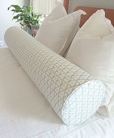 a bed with white pillows and a rolled up pillow