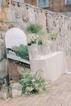 a table with flowers and vases on it next to a stone wall