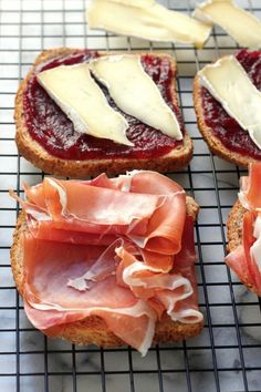 two pieces of bread with meat and cheese on them sitting on a cooling wire rack