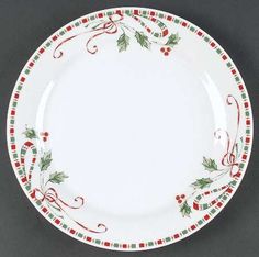 a white plate with holly and red berries on the rim is sitting on a gray surface