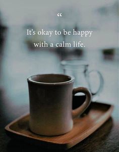 a coffee cup sitting on top of a wooden tray next to a glass jar with the words, it's okay to be happy with a calm life