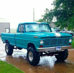 an old blue truck is parked in the rain