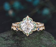 a diamond and emerald engagement ring on top of a rock