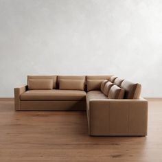 a brown couch sitting on top of a hard wood floor next to a white wall