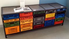 a book is sitting on top of a multi - colored cabinet with many bins