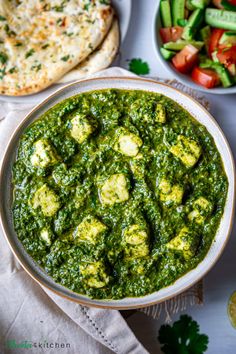 a bowl filled with spinach and bread next to other foods