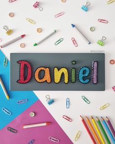 the word danielle spelled with crayons and pencils on top of colored paper