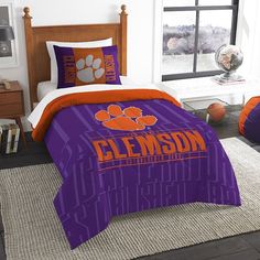 an orange and purple comforter set with clemson logo on the front in a bedroom