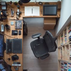 an overhead view of a computer desk with a chair in the middle and various electronics on it