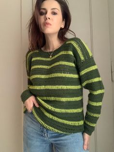 a woman standing in front of a door wearing a green and yellow striped knit sweater