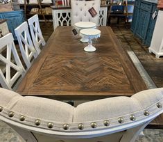 a dining room table with white chairs and a wooden centerpiece on top of it