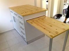 a kitchen island made out of plywood and metal legs with a person walking in the background