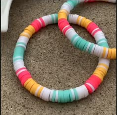 two colorful bracelets sitting on top of a floor next to a white plastic chair