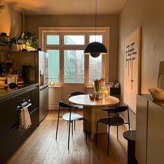 a kitchen with a table and chairs next to a window in the middle of it