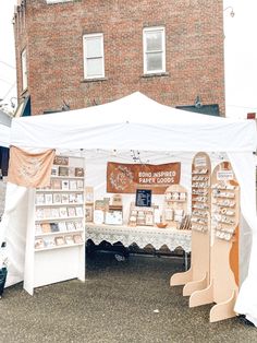 an outdoor booth with many items for sale on the table and in front of a brick building