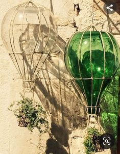 two green glass hot air balloons hanging on a wall next to a potted plant