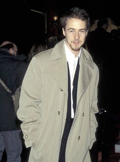 a man in a trench coat and tie at an event