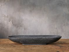 a large bowl sitting on top of a wooden table next to a gray concrete wall